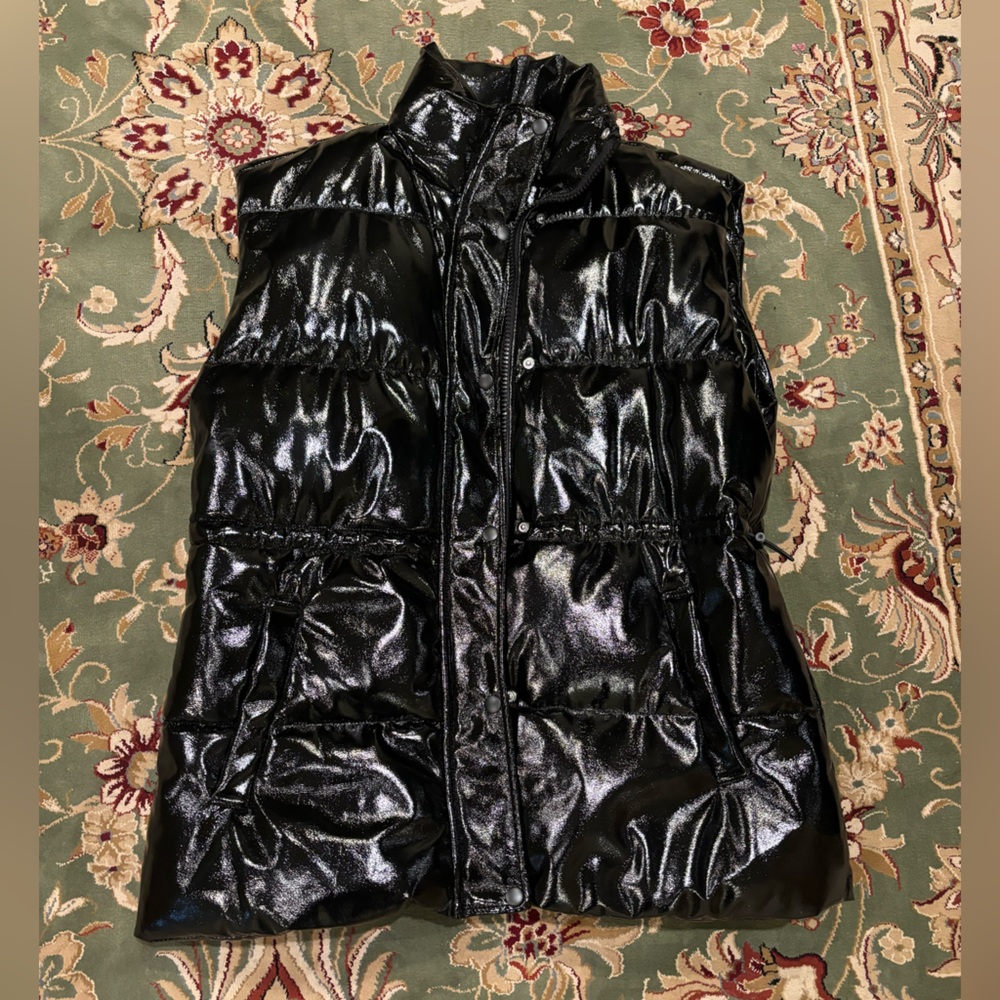 Black puffer metallic long vest with adjustable straps, zipper and buttons.